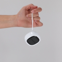 Mano sosteniendo un pequeño dispositivo solar blanco, mostrando su diseño compacto y funcionalidad ecológica.