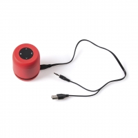 Altavoz rojo y negro con botones de funciones al centro, junto con cable generador de carga.