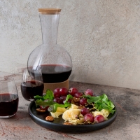 Botella con vino al lado de un plato de ensalada. 